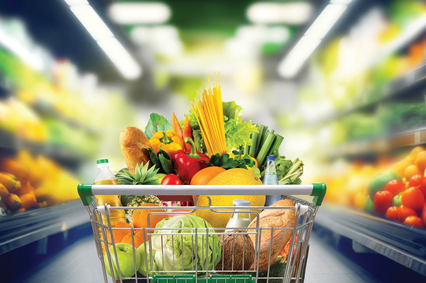 Shopping cart full of groceries at the supermarket aisle.